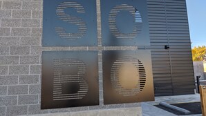Une façade d’immeuble ornée d’une enseigne métallique sur laquelle figurent les chiffres « 50 » et « 80 ».