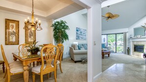 A spacious living room with a dining area, a fireplace, and a ceiling fan.