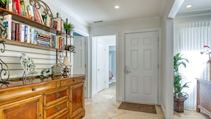 A hallway with a wooden cabinet, bookshelves, and a door.