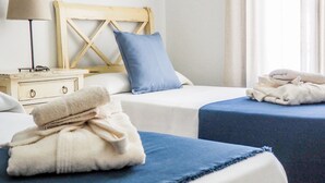 Una habitación de hotel con dos camas, una mesita de noche, una lámpara y una ventana con cortinas.