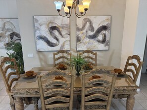 Un espace repas comprenant une grande table, des chaises décorées et des œuvres d’art murales.