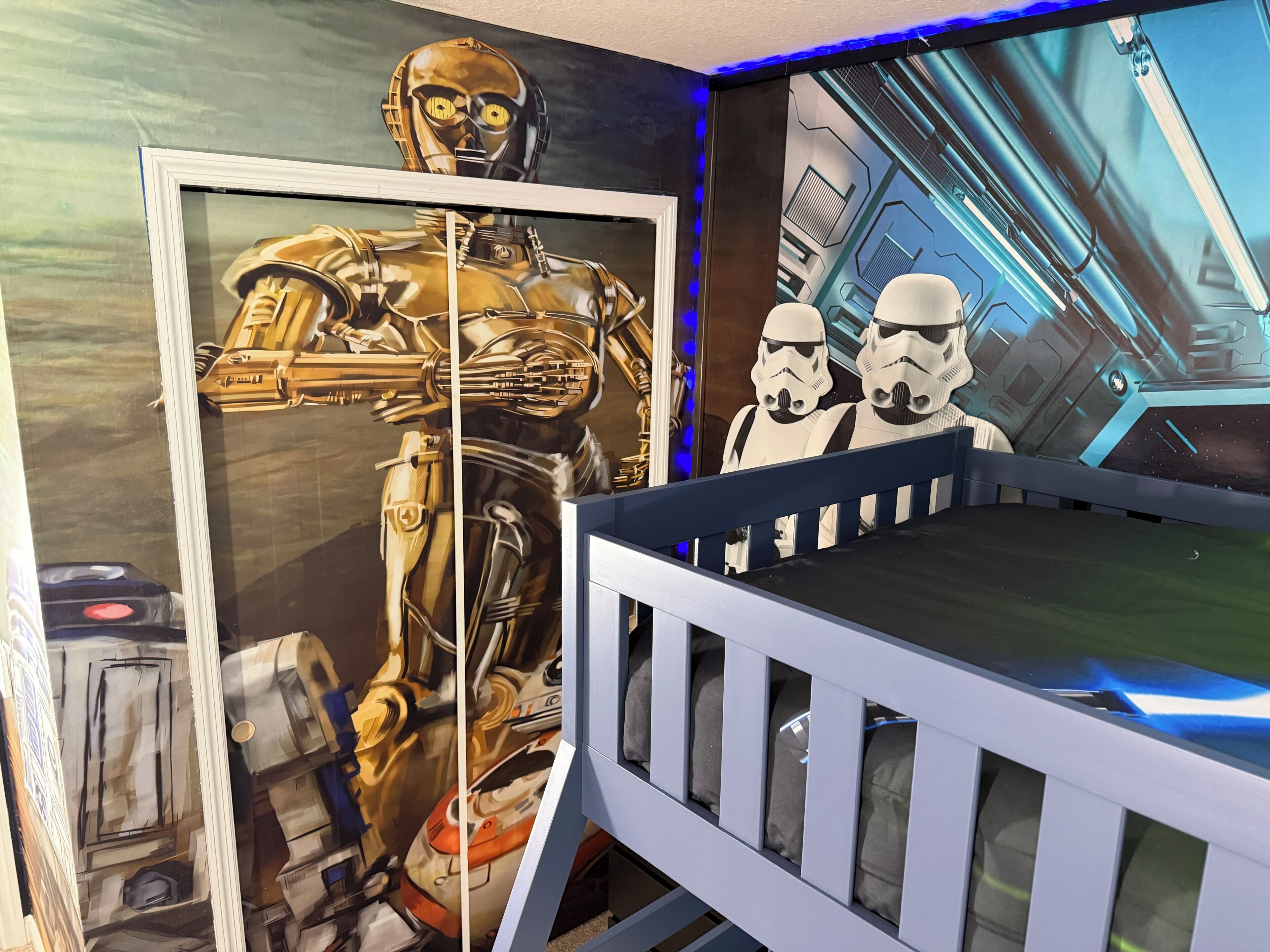 A room with a Star Wars-themed wall, a crib, and a Star Wars poster.
