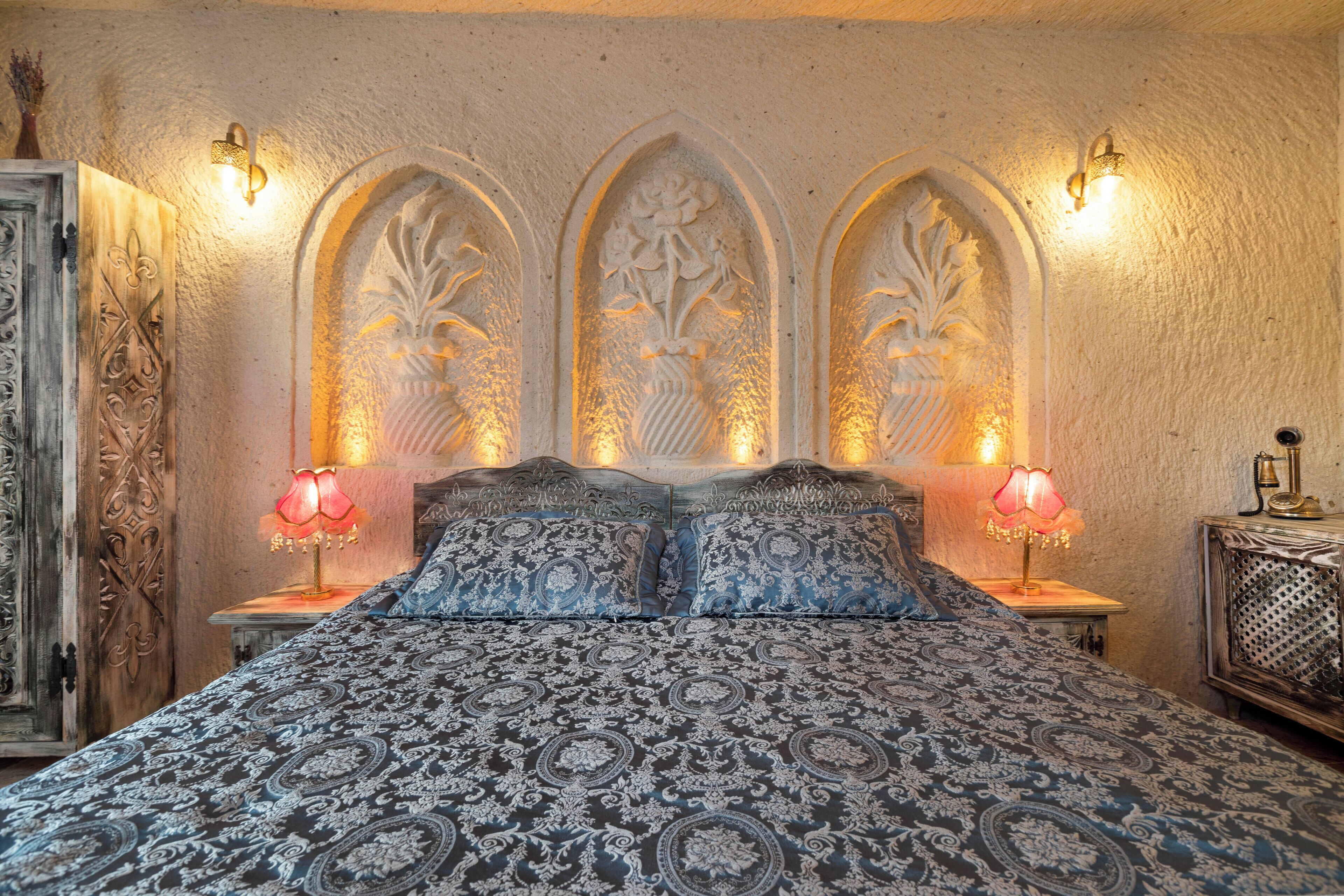 A bedroom with a large bed, ornate headboard, and two bedside lamps.