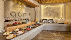 A buffet setup with various food items and a decorative wall with a horse relief. - Acer Cave Hotel (Ürgüp)