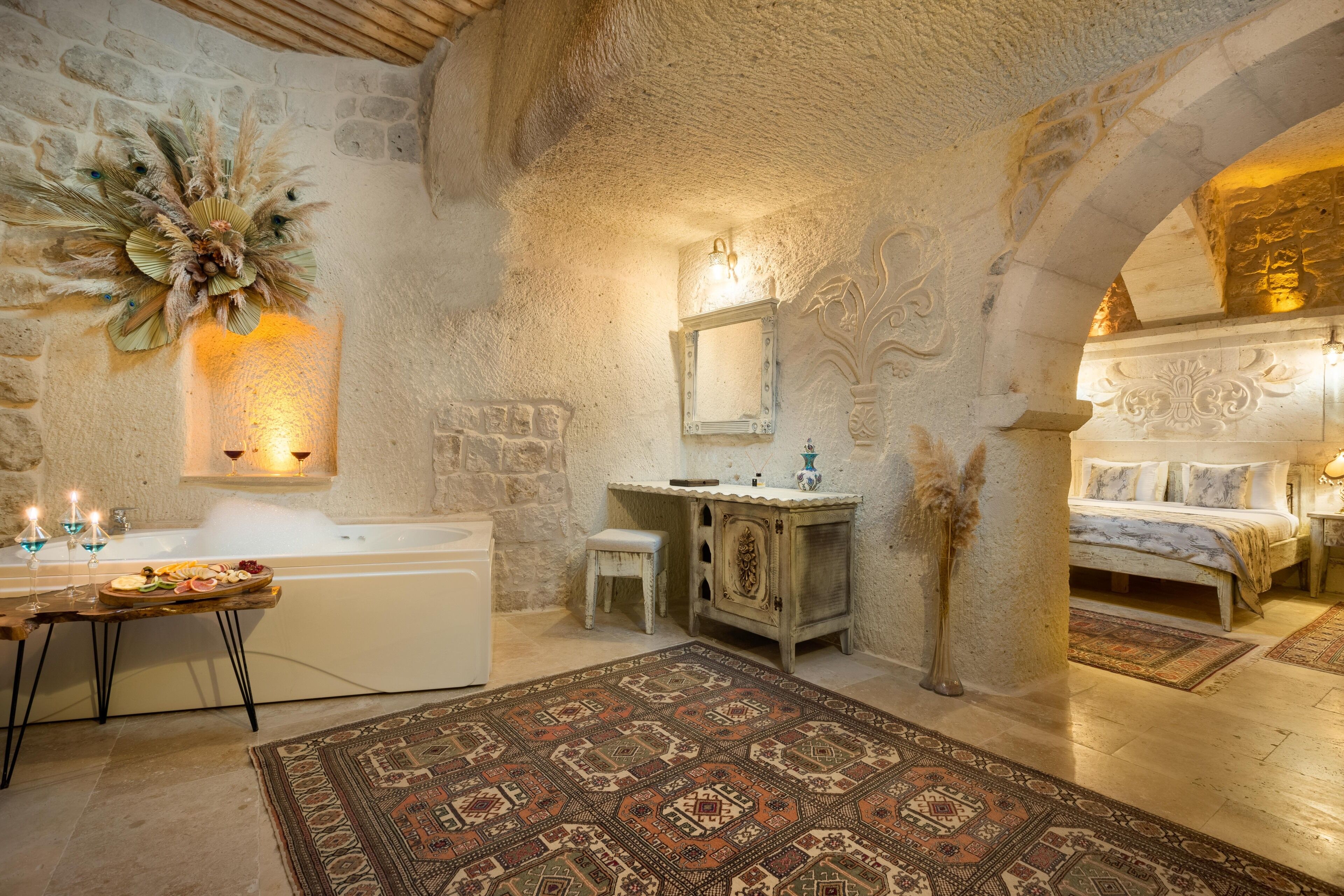 Un baño rústico con pared de piedra, una bañera, un lavamanos y una cama.