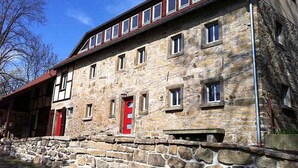 A stone building with multiple windows and a red door.