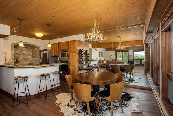 A spacious kitchen with wooden cabinets, a stone fireplace, and a large island with bar stools.
