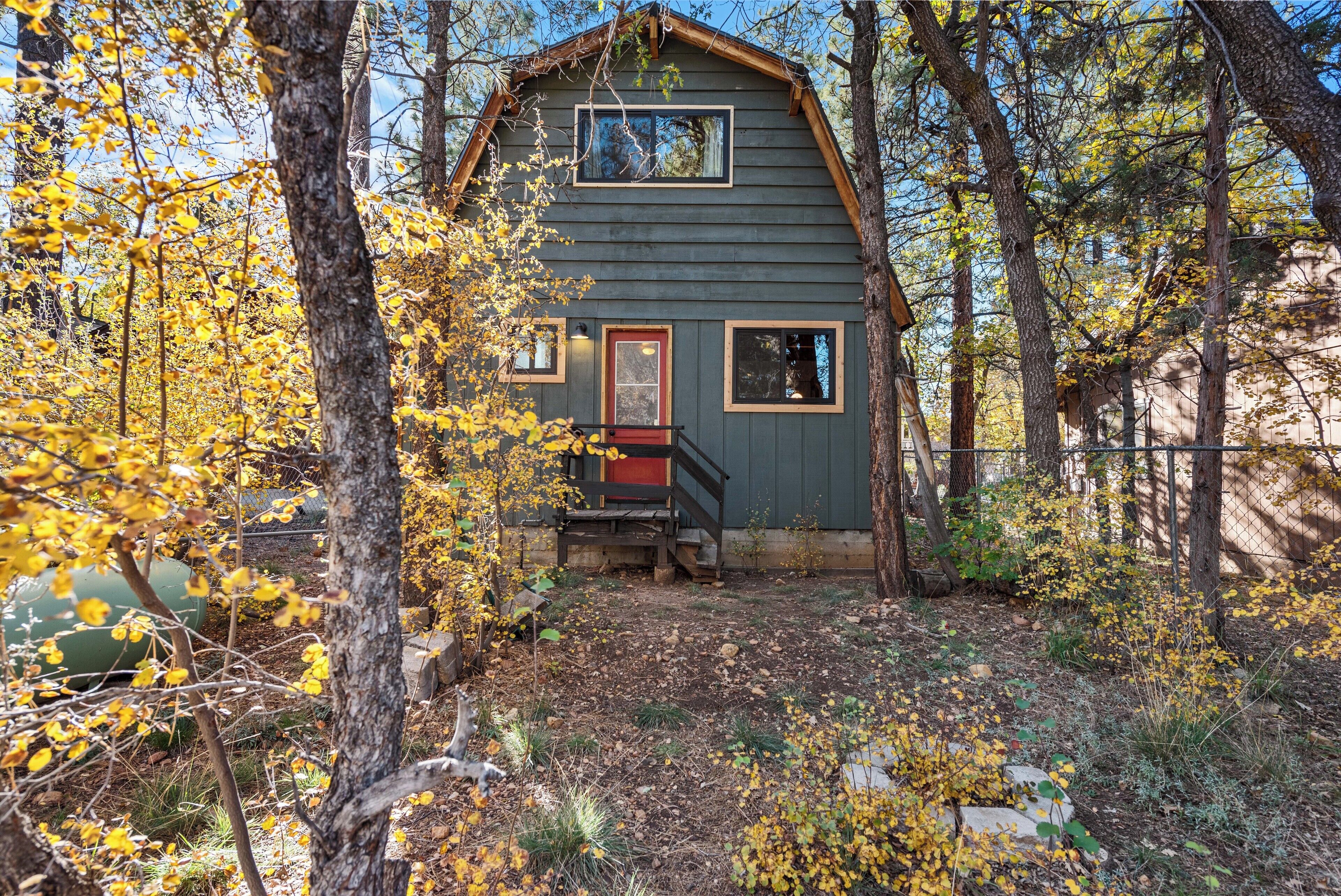 A rustic cabin with a wooden exterior, a red door, and a small porch.
