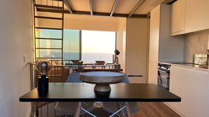 Une cuisine moderne dotée d’une grande fenêtre donnant sur la mer, une table à manger ronde et une vue sur le balcon.
