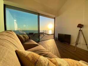 Una sala de estar moderna con un sofá grande, un televisor y una lámpara con trípode.
