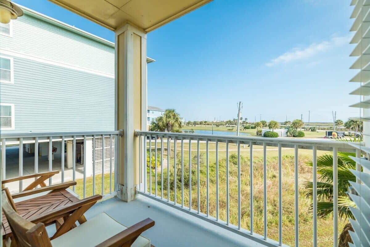 Un balcone con vista su una zona verde e un edificio sullo sfondo.