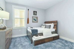 A bedroom with a bed, a dresser, a window with blinds, and wall art.