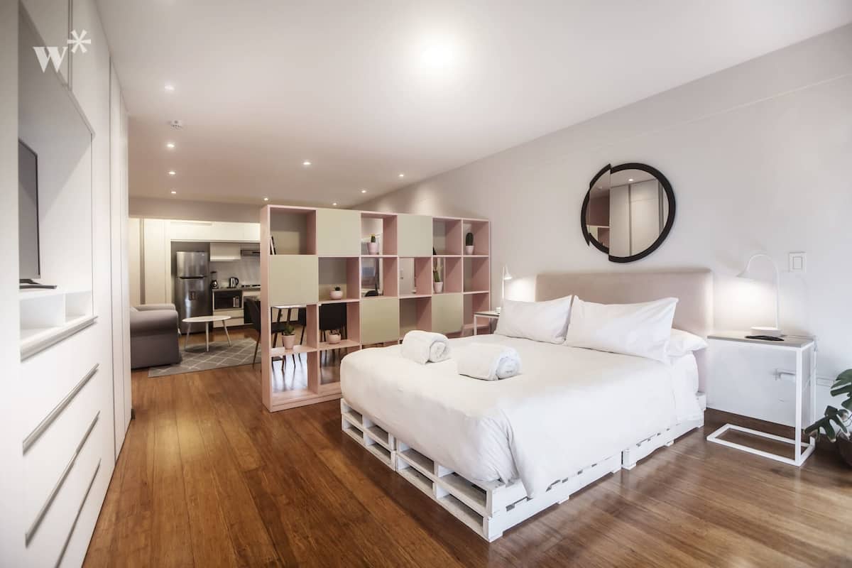 Ein modernes Schlafzimmer mit einem großen Bett, Nachttischen, einem Spiegel und einer eingebauten Regaleinheit.