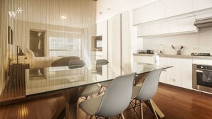 A modern kitchen with white cabinets, a stainless steel oven, and a glass dining table with chairs. - Wynwood Las Mimosas in Barranco (Lima)