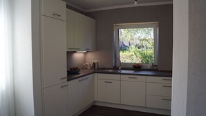 Una cocina moderna con armarios blancos, encimera oscura y ventana con vistas a zonas verdes.