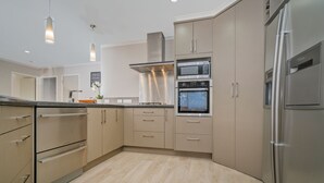Une cuisine moderne dotée d’appareils électroménagers en acier inoxydable, de meubles de couleur beige et d’un plancher en bois clair.
