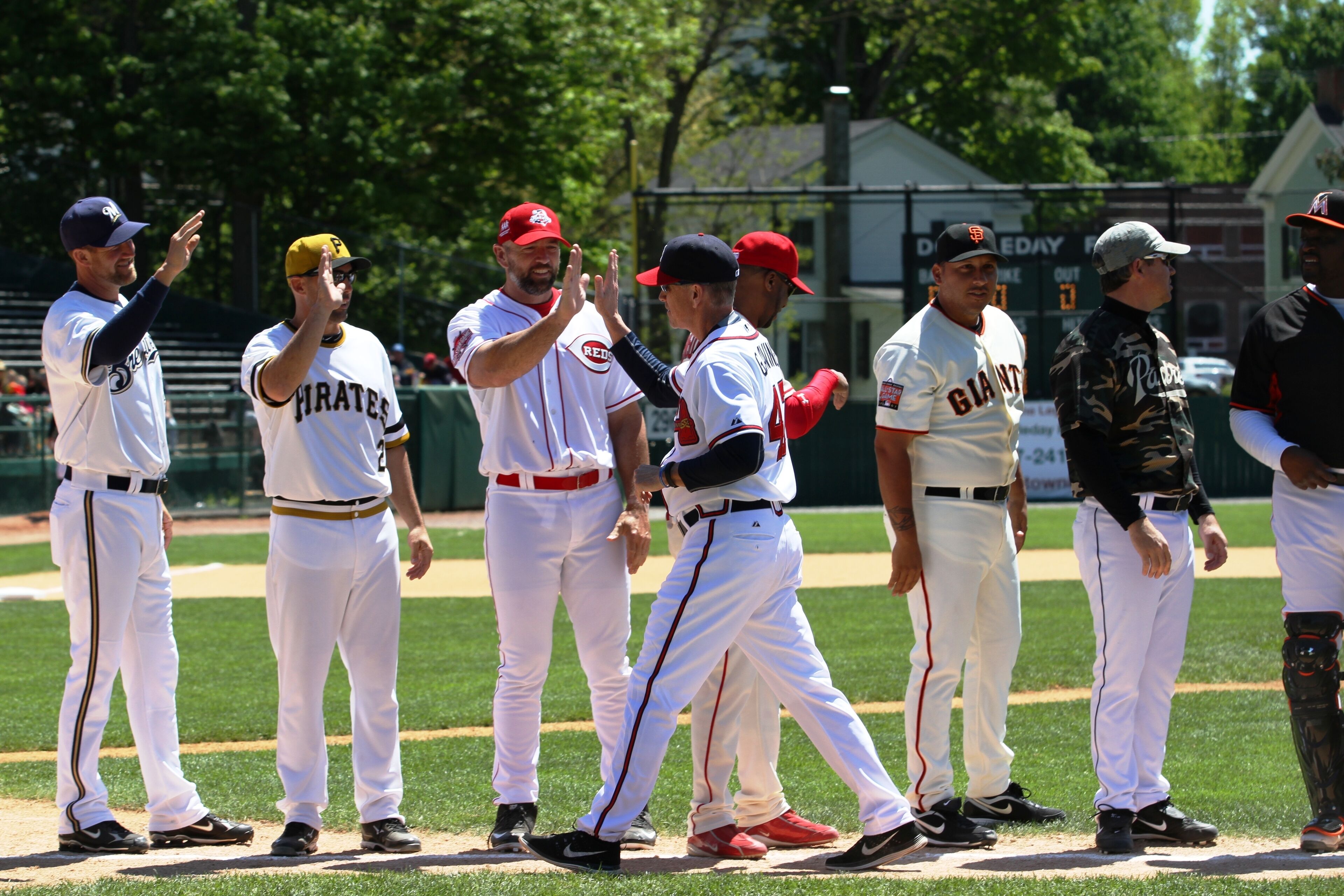 Ein Baseballfeld mit Spielern in weißen und roten Uniformen, die in einer Reihe stehen.
