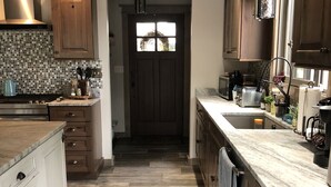 A kitchen with wooden cabinets, a tiled backsplash, and a patterned rug. - New waterfront house with deck,  dock, close to Old Forge, fireplace, , patio (Old Forge)