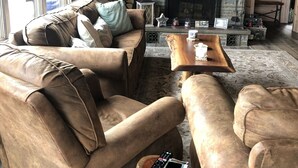 A cozy living room with a stone fireplace, leather sofas, and a flat-screen TV mounted above it. - New waterfront house with deck,  dock, close to Old Forge, fireplace, , patio (Old Forge)