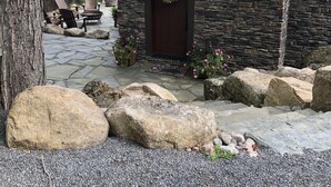 A stone building with a wooden door and a wreath. There are large rocks in front and a stone pathway leading to the door. - New waterfront house with deck,  dock, close to Old Forge, fireplace, , patio (Old Forge)