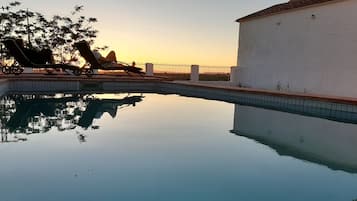 Relax by the pool surrounded by a low wall and lounge chairs.
