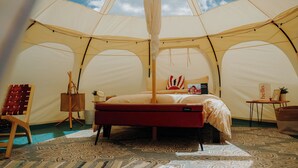 Una habitación con carpa, una cama, una pequeña mesa y una silla.