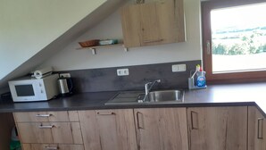 A kitchen with a microwave, toaster, sink, and wooden cabinets. - Ihr Ferienhof am Rande der Alpen, Nebenhaus (Seeg)