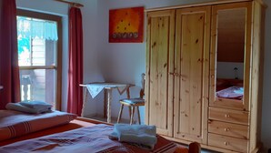A room with two beds, a wooden wardrobe, a small table, and a chair. - Ihr Ferienhof am Rande der Alpen, Nebenhaus (Seeg)