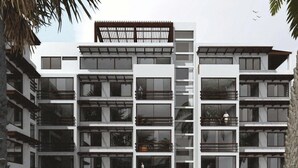 Un immeuble moderne à plusieurs étages, doté de balcons, de grandes fenêtres et d’un espace central ouvert.