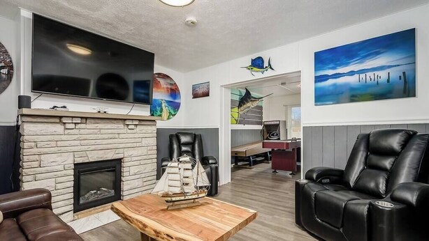 Ein Wohnzimmer mit Kamin, Ledersessel, Couchtisch aus Holz und Bildern an den Wänden.