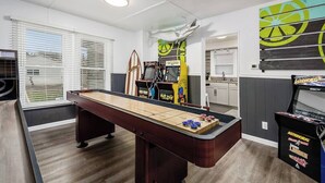 Ein Billardtisch, ein Tischfußballtisch und Spielautomaten in einem Raum mit Küchenzeile.