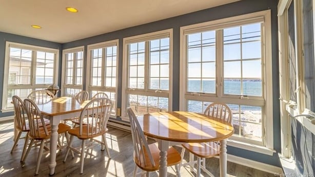 A dining area with a large table and chairs, large windows with ocean views, and a ceiling with recessed lighting. - Sleep to the sound of the waves. Watch the sun set from the deck! Secluded beach (East Lyme)