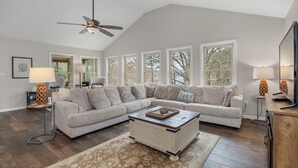 A spacious living room with a large sectional sofa, a coffee table, and a ceiling fan.