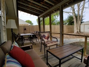 Relax in an outdoor space with a comfortable sofa and dining area under a shaded pergola.