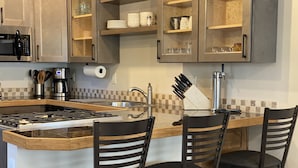 A kitchen with a central island, bar stools, a built-in stove, and a coffee maker. - Quiet Old Town Retreat/Pet Friendly
2 King Suites/Beer Tap/EV/AC (Steamboat Springs)