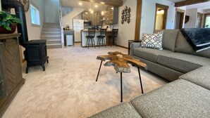 A spacious living area with a sofa, a unique wooden coffee table, and a kitchen in the background. - Quiet Old Town Retreat/Pet Friendly
2 King Suites/Beer Tap/EV/AC (Steamboat Springs)