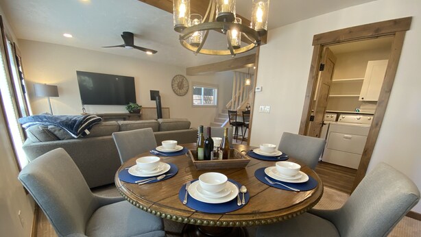 A dining area with a round table set for four, surrounded by grey upholstered chairs. - Quiet Old Town Retreat/Pet Friendly
2 King Suites/Beer Tap/EV/AC (Steamboat Springs)