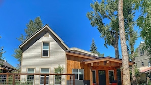 A two-story house with a wooden porch and a stone retaining wall. - Quiet Old Town Retreat/Pet Friendly
2 King Suites/Beer Tap/EV/AC (Steamboat Springs)