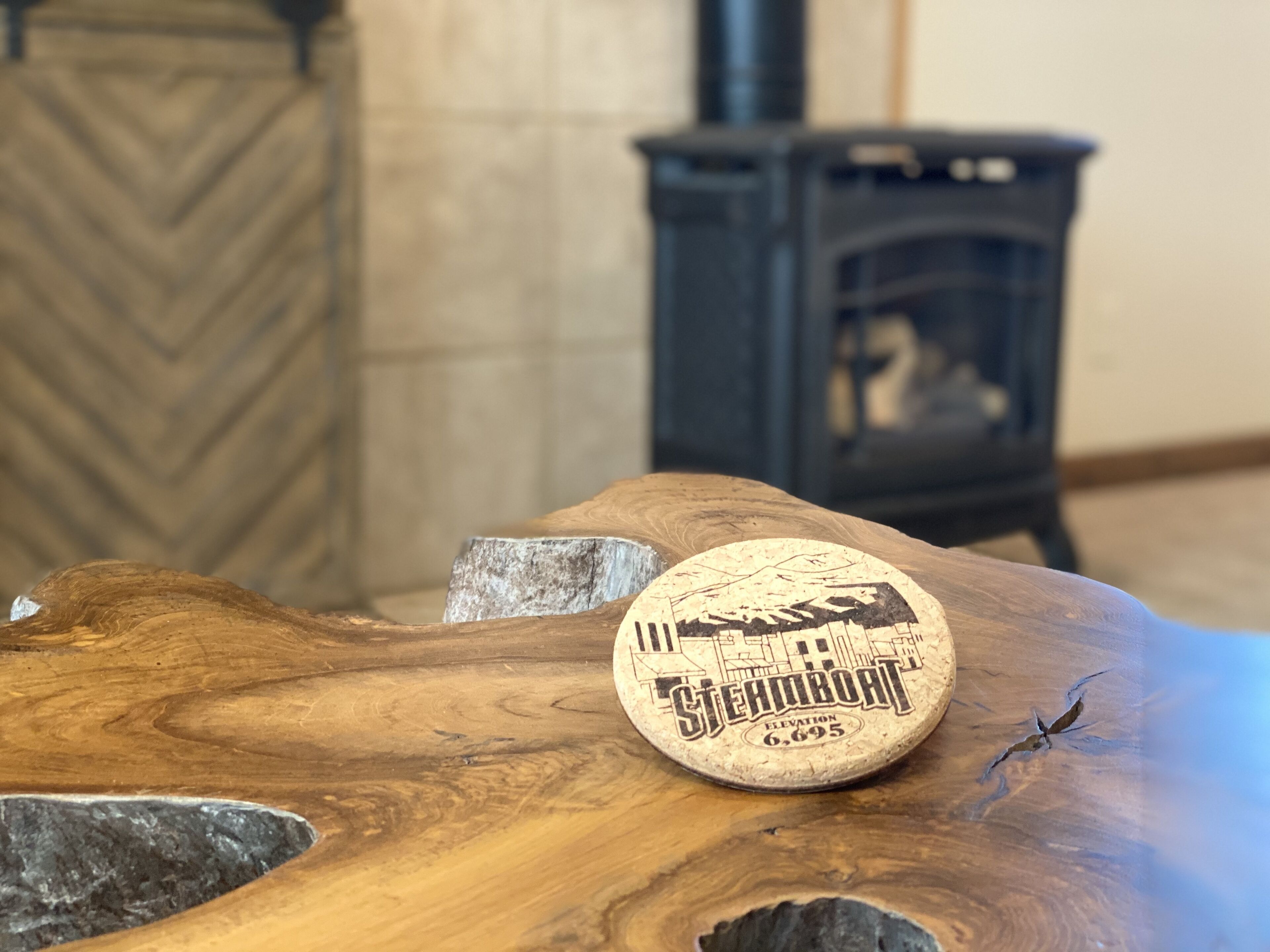 Une table en bois sur laquelle repose un dessous de verre orné d’une vue de la ville et des inscriptions « Steamboat » et « Élévation 6 695 ».