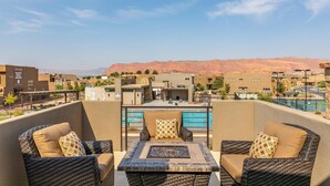 Terraza en la azotea con mobiliario de mimbre, piscina y vistas a montañas distantes.