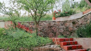 A stone staircase leading up to a garden area with a table and a metal bench. - Nice Cozy Apartment in Juriquilla (Qro.)