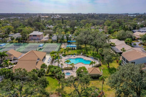 Residents can enjoy a serene environment surrounded by lush greenery and palm trees, with a swimming pool and tennis courts nearby.