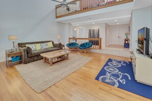Relax in this spacious living area with a high ceiling, comfortable sofa set, and large window.