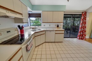 Compact kitchen with oven, sink, and dishwasher, offering a view of the outdoors.