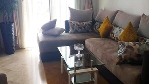 A living room with a sofa, a glass coffee table, and a potted plant. - Residence Hivernage Founty 4773 (Agadir)