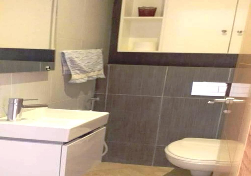 Een badkamer met een wit wastafel, een toilet en een handdoek aan de muur.