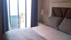 A hotel room with a bed, a nightstand, a lamp, and a view through a window. - Residence Hivernage Founty 4773 (Agadir)