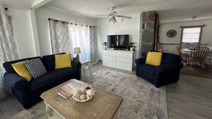 A living room with two sofas, a coffee table, a TV, and a dining area with chairs and a table. - Beach Vacation Getaway (Old Orchard Beach)