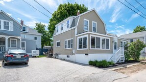 A two-story house with a front porch, a driveway, and a car parked in the driveway. - Beach Vacation Getaway (Old Orchard Beach)