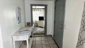 A hallway with a white door, a white console table, and a tiled floor. - Beach Vacation Getaway (Old Orchard Beach)